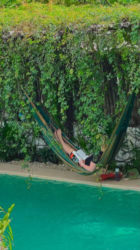 a woman laying in a hammock next to a body of water at Hotel Jaiba Mahahual - Adults Only in Mahahual