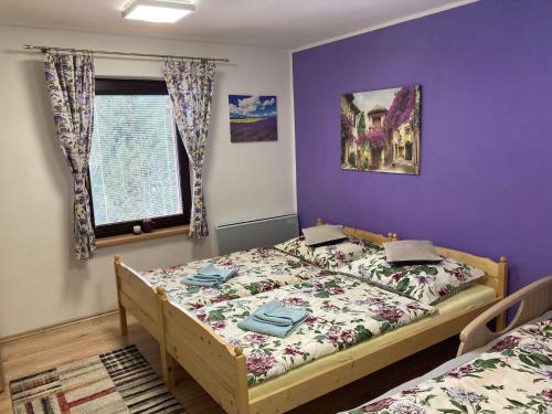 a bedroom with two beds and a purple wall at Penzion Karolinka in Karolinka