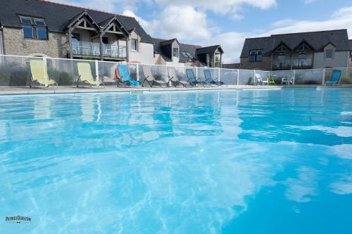 una gran piscina con sillas y agua azul en Apparthôtel Mont Saint Michel - Résidence Fleurdumont en Beauvoir