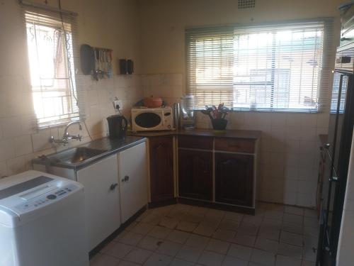 een kleine keuken met een wastafel en een magnetron bij Feel at home stay in Bloemfontein