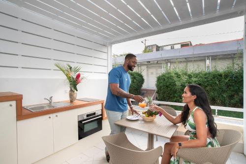 a man and a woman sitting at a table on a patio at Karibea Squash Hôtel in Fort-de-France