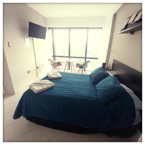 a bedroom with a bed with a blue comforter and a large window at Executive suite in gastronomic district in Valencia