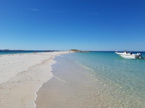 a boat in the water next to a beach at La Maison Keribin in Moëlan-sur-Mer