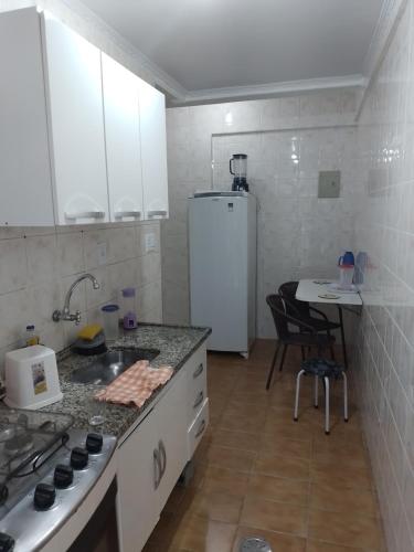 Il comprend une cuisine équipée d'une cuisinière et d'un réfrigérateur blanc. dans l'établissement Coração da Ocian, à Praia Grande