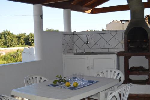 a white kitchen with a table and chairs and a stove at Quinta das Figueiras in Vila Nova De Cacela