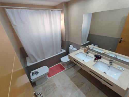 y baño con 2 lavabos, aseo y espejo. en Villa Aguilas Club Guest house, en Málaga