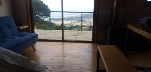 a living room with a blue couch and a large window at Reserva Los Maquis in Cobquecura