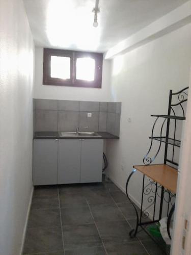 une petite cuisine avec un évier et une fenêtre dans l'établissement Résidence du Houx - 2 (Astérix, Aéroport CDG...), à Survilliers