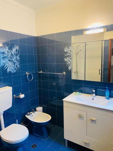 a blue tiled bathroom with a toilet and a sink at SwordFish Beach House in Peniche