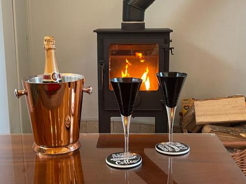 a bottle of champagne and two glasses on a table with a fireplace at Artists’ Cottages in Harrogate