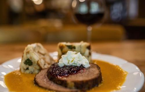 a plate of food on a table with a glass of wine at Penzion Panský dům in Kvilda