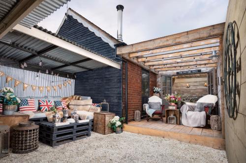 an outdoor patio with a couch and chairs at The Old Parlour at Cheshire Boutique Barns in Nantwich