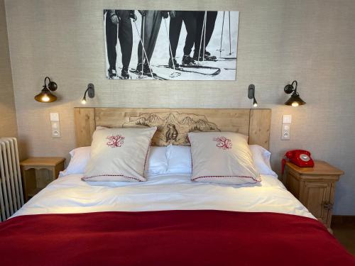 a bed with two pillows and a picture on the wall at Hôtel du Lion d'Or in Cauterets