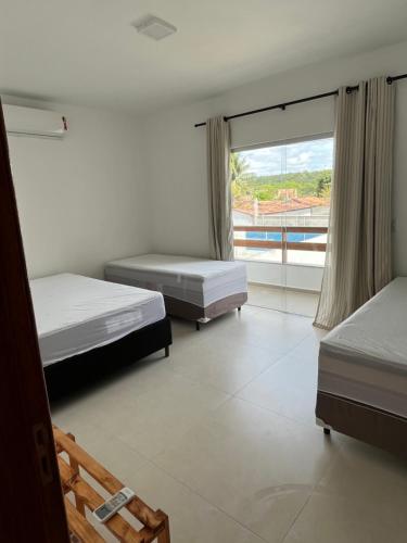 1 Schlafzimmer mit 2 Betten und einem großen Fenster in der Unterkunft Casa com piscina em Coroa Vermelha in Santa Cruz Cabrália