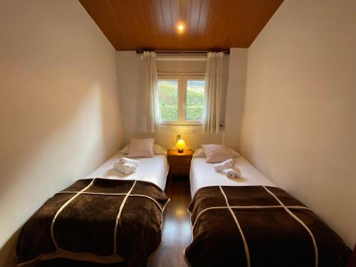 2 camas en una habitación pequeña con ventana en Ed. Euro Àtic en Encamp