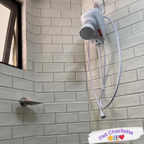un cabezal de ducha en una pared de ladrillo blanco en Flat Charllotte, en Porto de Galinhas