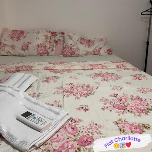 una cama con un celular sentado encima de ella en Flat Charllotte, en Porto de Galinhas