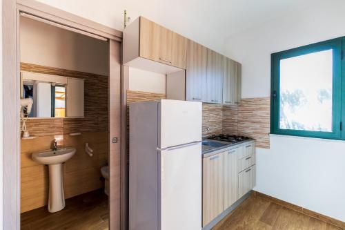 a small kitchen with a refrigerator and a sink at Villaggio Residence Pietra Grigia in Marina di Camerota