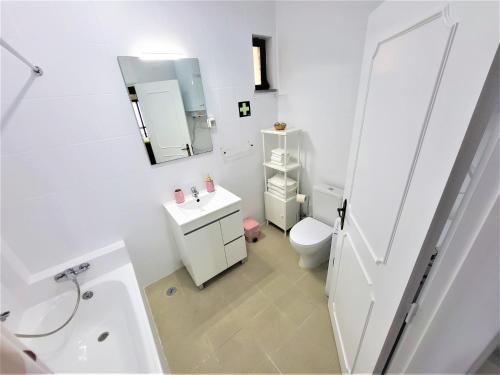 La salle de bains blanche est pourvue de toilettes et d'un lavabo. dans l'établissement Apartamento Praia Fuzeta 2, à Fuzeta