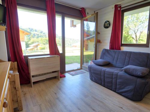 - un salon avec un canapé bleu et des portes coulissantes en verre dans l'établissement Charmant studio avec terrasse et parking couvert - FR-1-505-49, à Notre-Dame-de-Bellecombe