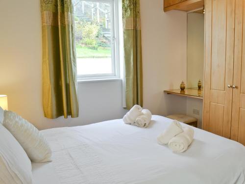 1 dormitorio con 2 toallas en una cama con ventana en Spout Crag Boathouse, en Far Sawrey