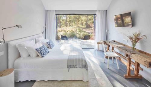 um quarto com uma cama, uma secretária e uma janela em Sublime Comporta Country Retreat & SPA em Comporta