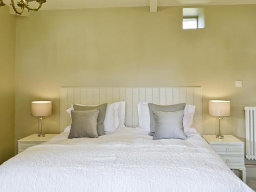a bedroom with a white bed with two lamps at The Dovecote in Romaldkirk
