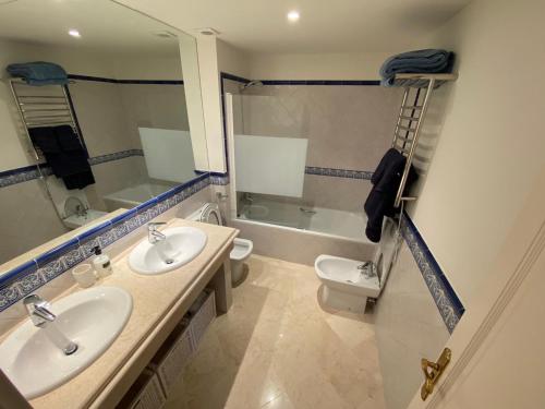 a bathroom with two sinks and a toilet and a tub at Stylish 3 bed house 2 bathrooms with patio, roof terrace and communal pool 5 minutes away from the beautiful Spanish white village of Casares Pueblo and only 20 mins from the sea in Casares