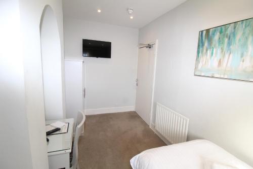 a white room with a bed and a tv on the wall at The Conningbrook Hotel in Ashford