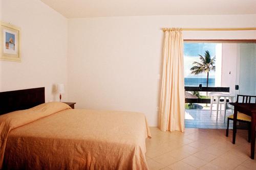 a bedroom with a bed and a view of the ocean at Hotel La Dolce Vita in Ilhéus