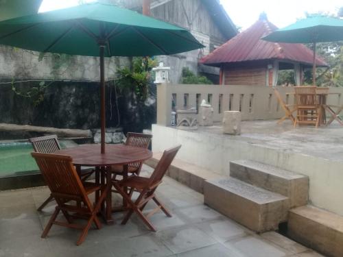 a table and chairs with an umbrella on a patio at Villa Names2 Gunung Bunder in Gunungpicung