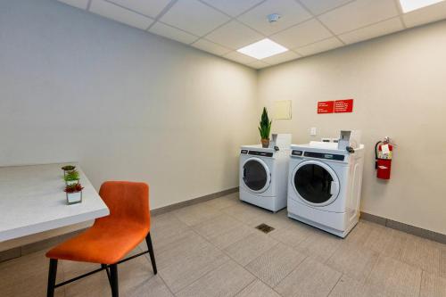 a laundry room with a washing machine and a chair at Avid Hotels - Denver Airport Area by IHG in Denver