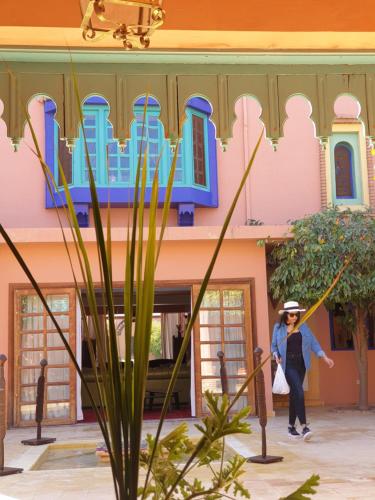 a woman walking in front of a pink building at Casa Taos in Marrakech