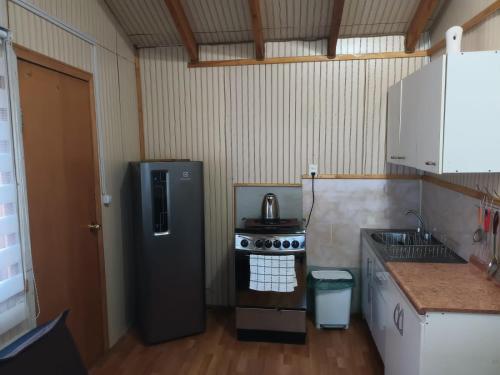 uma pequena cozinha com um frigorífico e um fogão em Cabañas Érica em Choshuenco