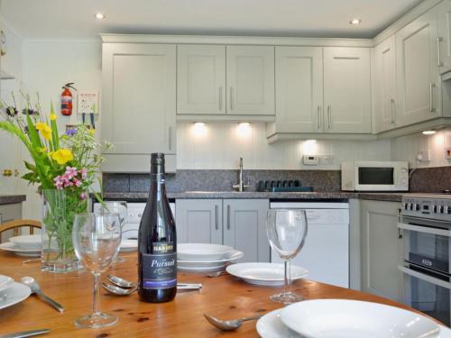 a kitchen with a table with a bottle of wine and glasses at Ashburn Cottage in Sallachy