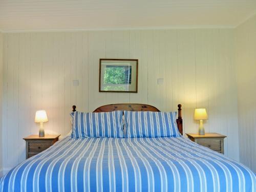 a bedroom with a bed with blue and white stripes at Ashburn Cottage in Sallachy