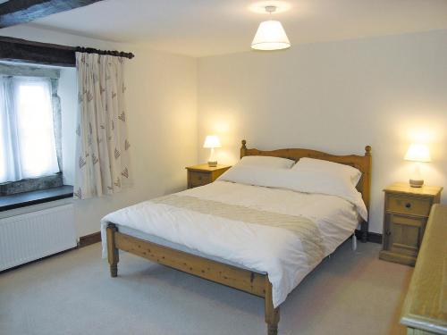 a bedroom with a bed with two night stands and two lamps at Angram Farmhouse in Deepdale