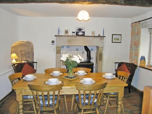 a dining room with a table and chairs and a fireplace at Angram Farmhouse in Deepdale