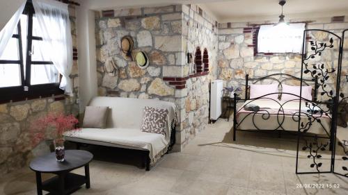 a bedroom with a stone wall with a bed and a table at Artemis Stone House in Psakoudia