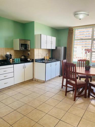 a kitchen with white cabinets and a table and a dining room at Oceanic 2 Bedroom Apartment - City View - Self-Catering in Durban