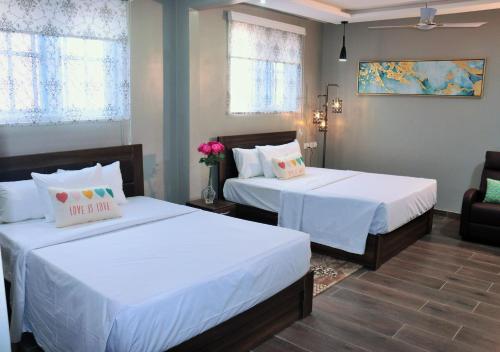 1 dormitorio con 2 camas con sábanas blancas en Lady M guest House en Tema