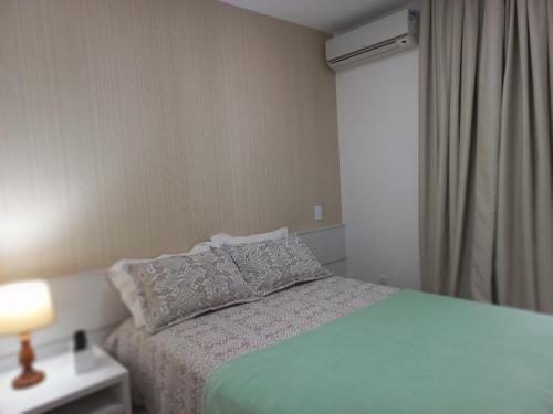 um quarto com uma cama com uma almofada e um candeeiro em Apartamento Em Condominio Residencial Familiar em Cabo Frio