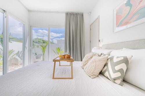 a white bedroom with a bed and a table at Caya Erasmus 20 in Tanki Lender