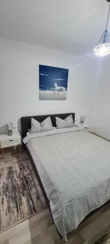 a white bedroom with a bed and a painting on the wall at La Andrei in Bistriţa