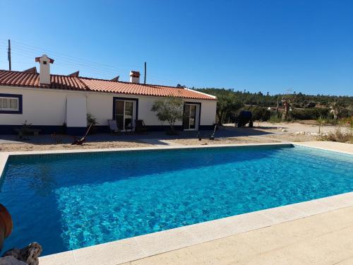 a large blue swimming pool in front of a house at Monte das Rolas - A Serenidade mora Aqui! in Ferraria