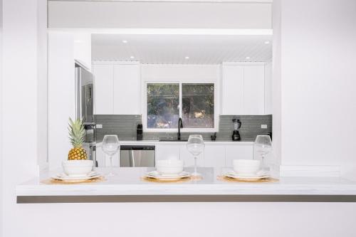 a white kitchen with glasses and plates on a counter at Salinja Cerca 2-B in Palm-Eagle Beach