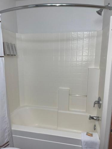 La salle de bains est pourvue d'une baignoire blanche et d'une douche. dans l'établissement Boothill Inn and Suites, à Billings