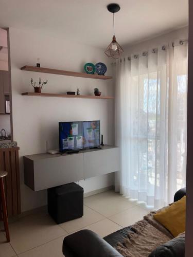 ein Wohnzimmer mit einem Sofa, einem Tisch und einem Fenster in der Unterkunft Apartamento próximo ao Parque e Aeroporto - com academia e piscina in Uberlândia