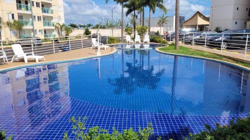 a swimming pool with blue water in a resort at Apartamento próximo ao Parque e Aeroporto - com academia e piscina in Uberlândia