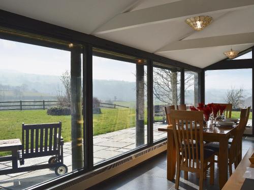 a dining room with a table and glass windows at Cennen Cottages- Longhouse in Ffair-fâch